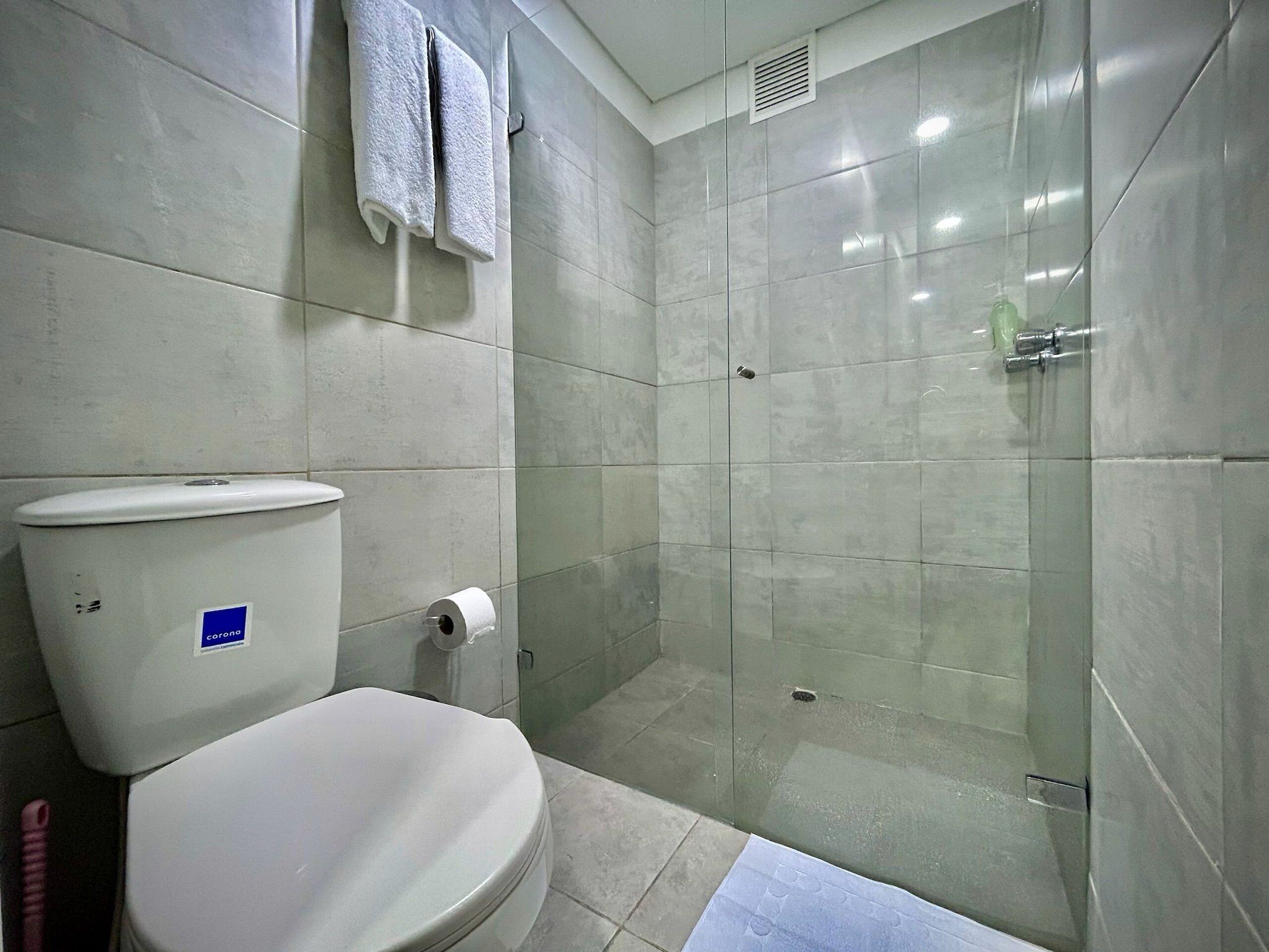 A bathroom with a toilet, a glass shower enclosure, and a towel rack.