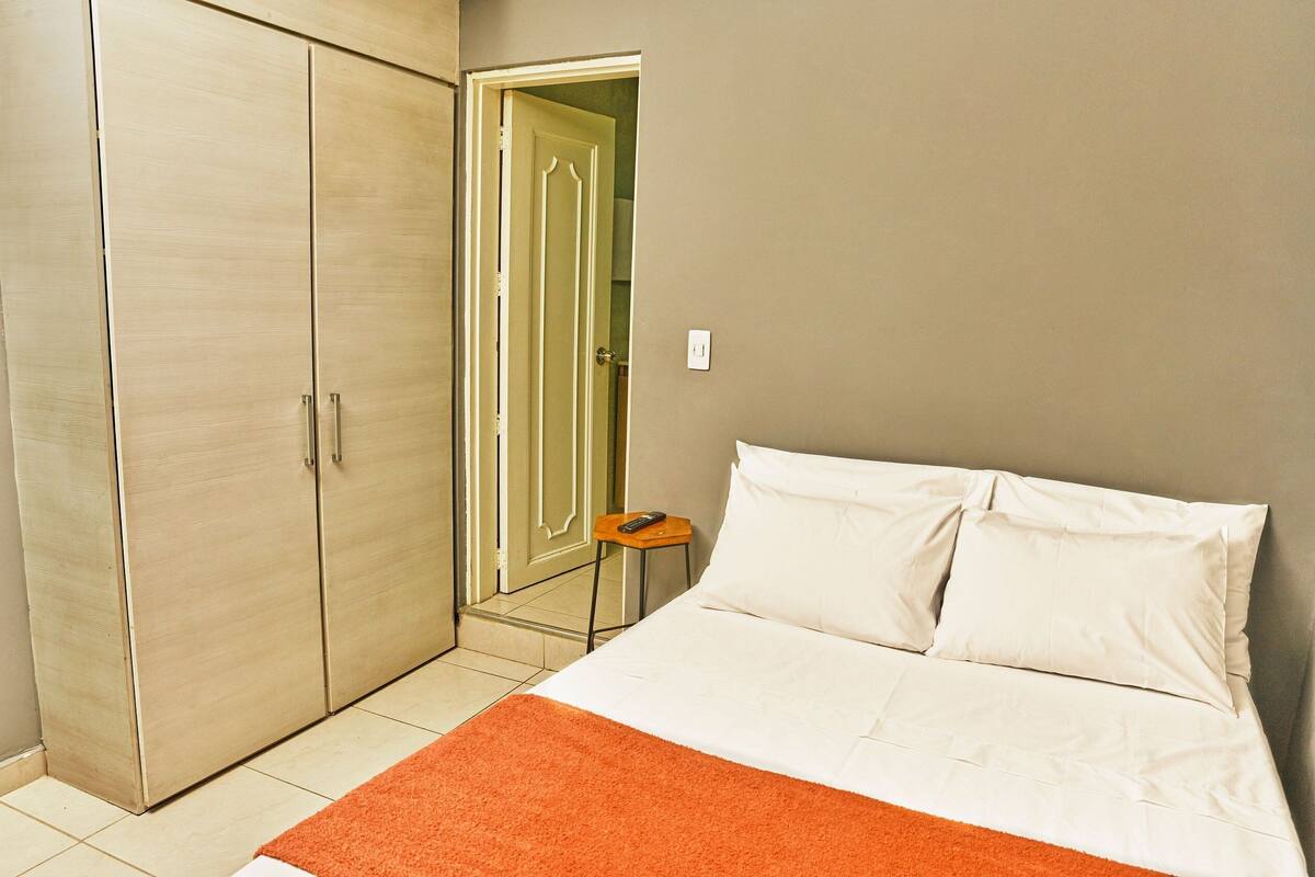 Een slaapkamer met een bed, een kledingkast en een deur naar een andere kamer.
