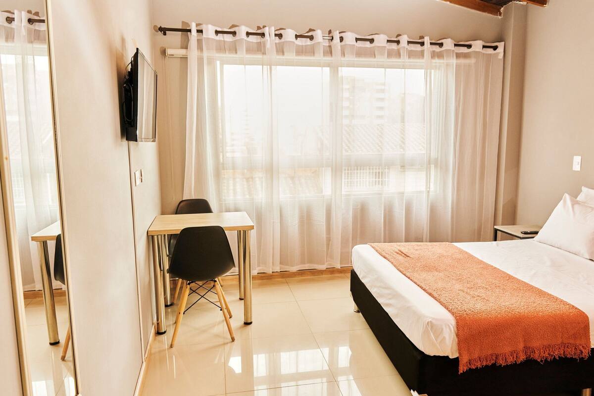 Een hotelkamer met een bed, een bureau en een stoel.