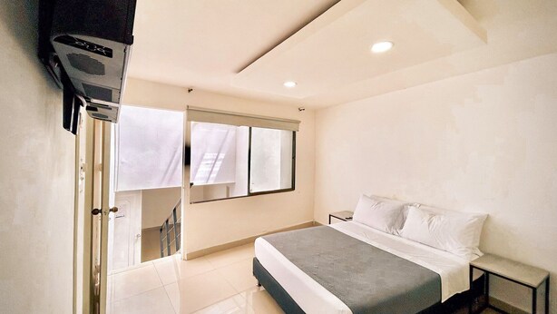 Een moderne slaapkamer met een bed, een klein nachtkastje, een spiegel en een douchehoek.