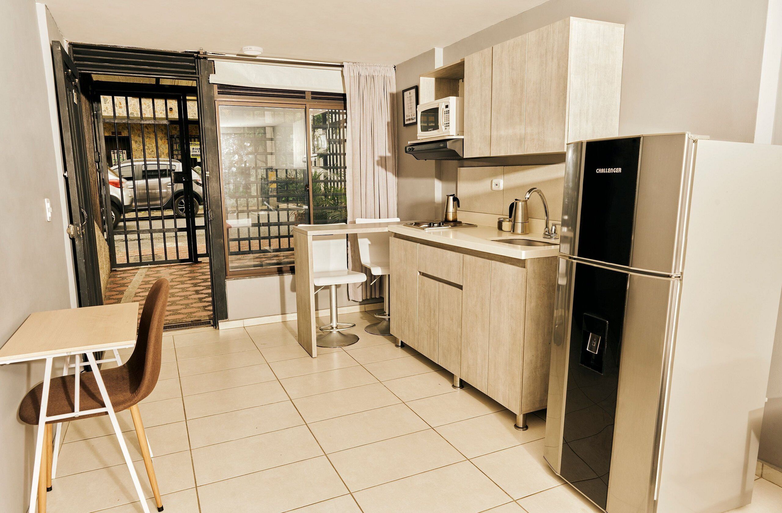 Cocina compacta con refrigerador, microondas y pileta.