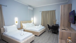 Habitación de hotel con dos camas, un escritorio, una silla, un televisor y un estante de madera con un tarro.