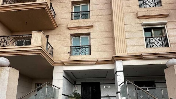 Un immeuble à plusieurs étages doté d’une entrée centrale, d’un escalier menant à l’entrée et d’un revêtement de sol à motifs.