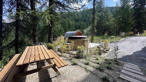 Ein Picknicktisch in bewaldeter Landschaft mit einer Badewanne und einem gepflasterten Weg.