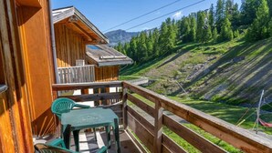 Eine Holzchalet mit Balkon, Tisch und zwei Stühlen.