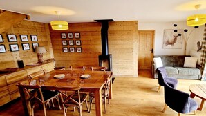 A cozy cabin interior with a wooden dining table and chairs, a sofa, and a fireplace. - 3rd floor, view mountain, balcony, parking, tv, ski locker, 123m², Montalbert (La Plagne)