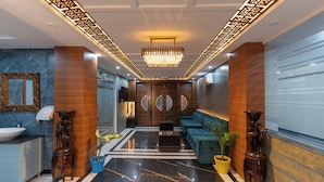 A modern lobby with a marble floor, a chandelier, a sofa, and a reception desk. - Riviera Resort  Rishikesh (Yamkeshwar)