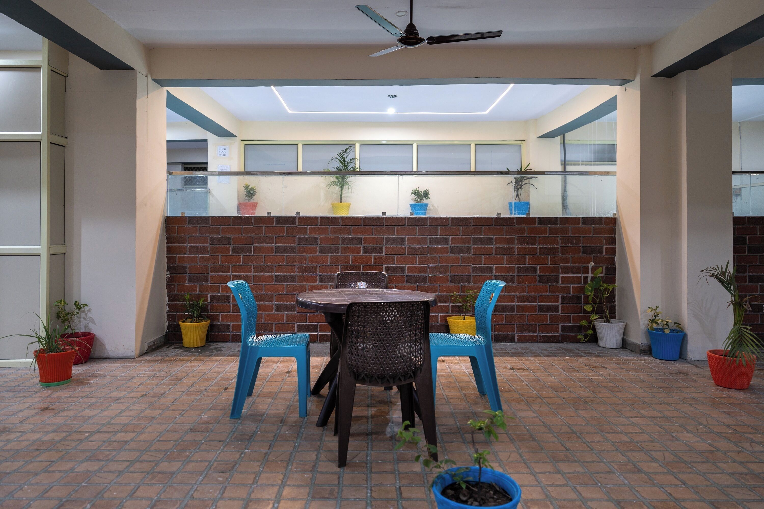 A patio area with a brick wall, a ceiling fan, and potted plants.