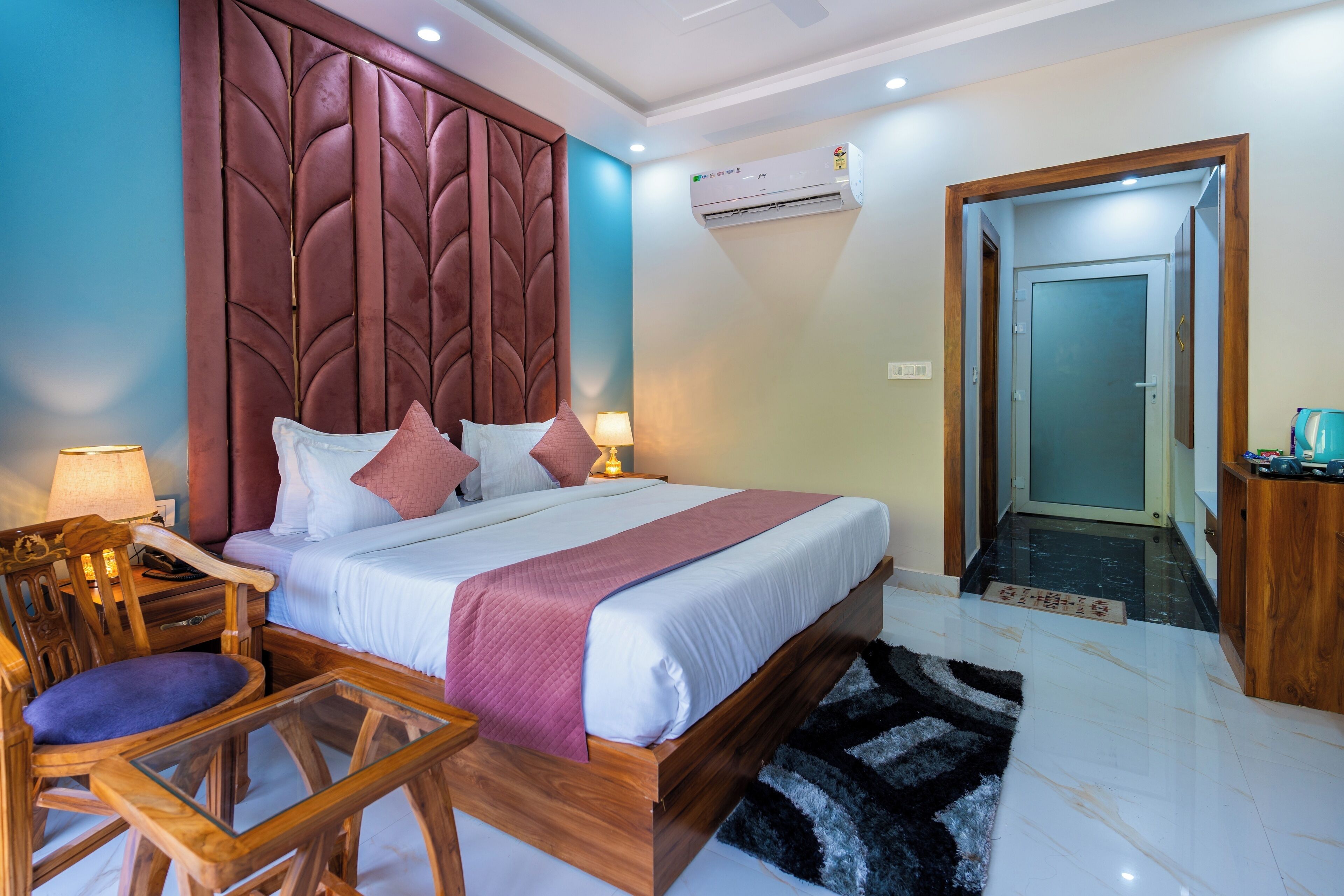 A hotel room with a large bed, a wooden headboard, a glass table, and a chair.