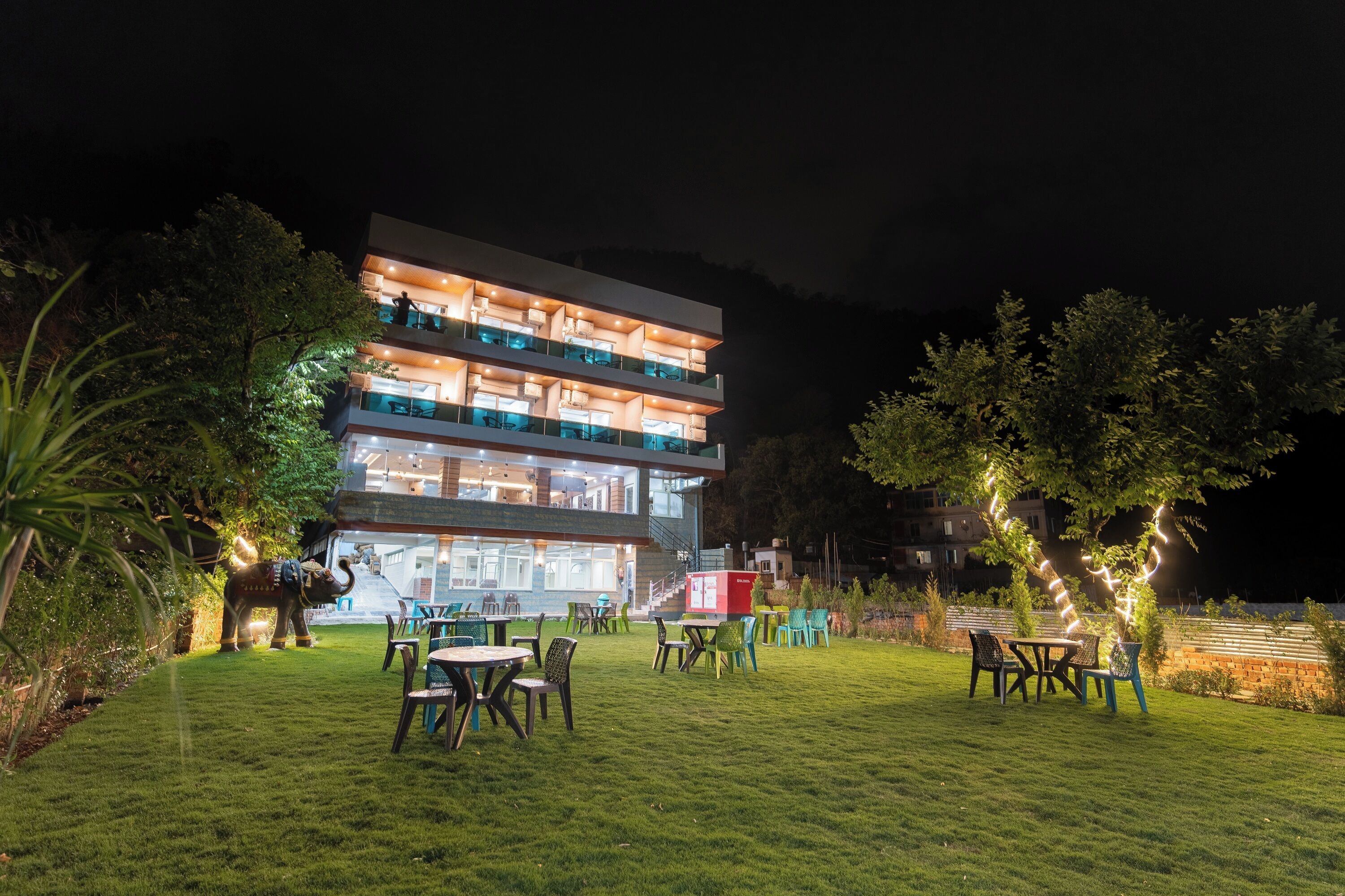 A multi-story hotel with outdoor seating and a well-lit entrance.