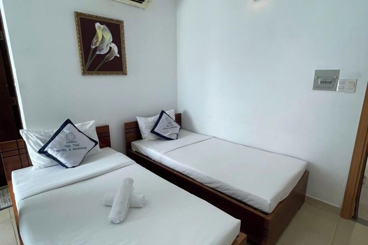 Ein Hotelzimmer mit zwei Einzelbetten, einem Bild an der Wand und einem kleinen Fenster.