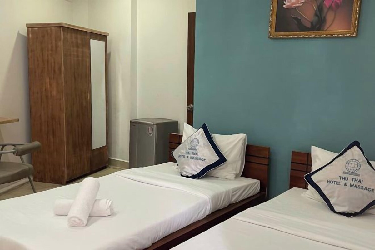 Habitación de hotel con dos camas, un armario de madera, un escritorio y un pequeño mueble.