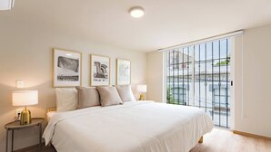 A bedroom with a large bed, two bedside tables with lamps, and three framed pictures on the wall.