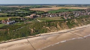 A coastal town with a beach, houses, and fields.