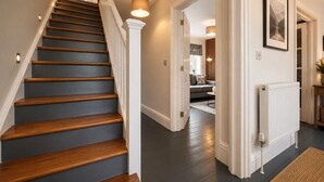 A staircase with wooden steps and white railings, leading to a living area with a sofa and a table.