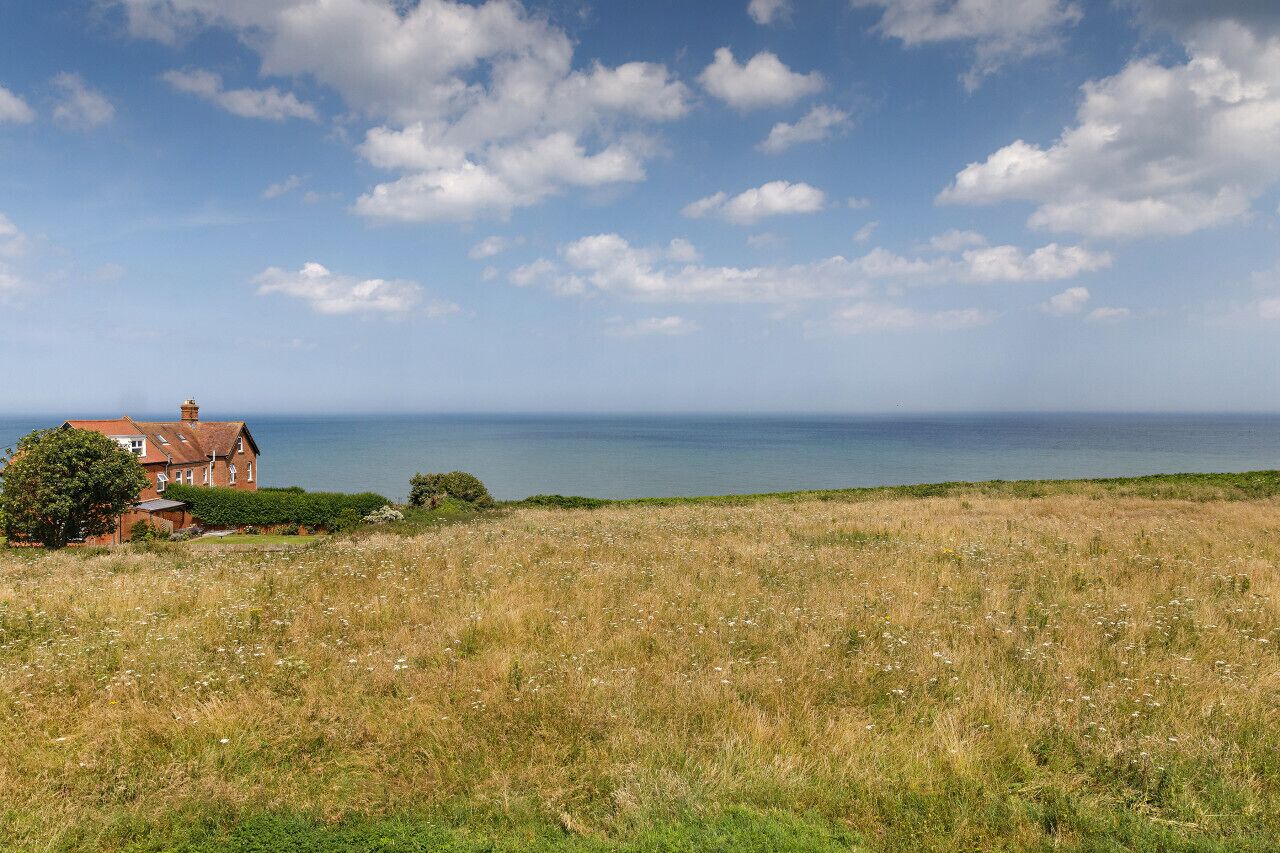 Een kustlandschap met een rode woning en een grasveld.