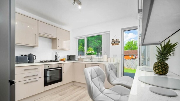 A modern kitchen with light wood cabinetry, a built-in oven, and a large window offering a view of the outdoors. - Birmingham Blissful Retreat - 3 Bed House (Birmingham)