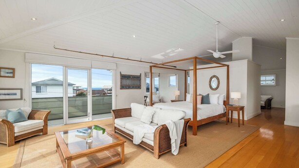 Une pièce spacieuse avec un grand lit, un canapé, une table basse et un ventilateur de plafond.