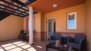 Un patio iluminado por el sol con una mesa, sillas y un sofá.
