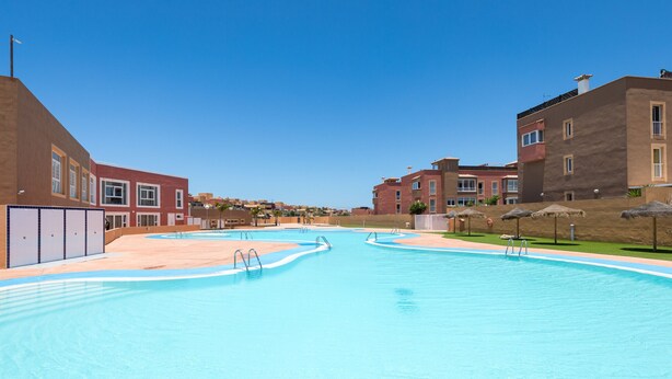 Una piscina con agua azul cristalina, rodeada de edificios de estilo arquitectónico moderno.