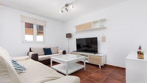 Una sala de estar moderna con un sofá, una mesa de centro, un televisor y estanterías empotradas.