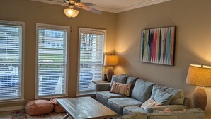 A living room with a sofa, a coffee table, a lamp, and a ceiling fan. - Beach Beau (Long Beach)