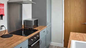 A kitchen with a built-in stove, oven, microwave, and grey cabinets. - Curlew Cottage - UK47697 (Haydon Bridge)
