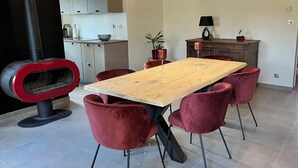 A modern kitchen with a central island, red chairs, and a wooden dining table. - Gîte La Rosalie (La Forestière)