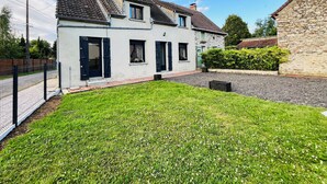 A two-story house with a tiled roof, a fenced yard, and a stone wall. - Gîte La Rosalie (La Forestière)