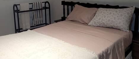 A bedroom with a bed, a nightstand, a wall-mounted painting, and a window.