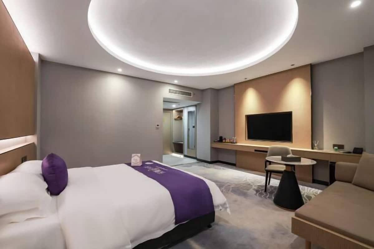 Una habitación de hotel moderna con una cama grande, un escritorio, una silla y un televisor.