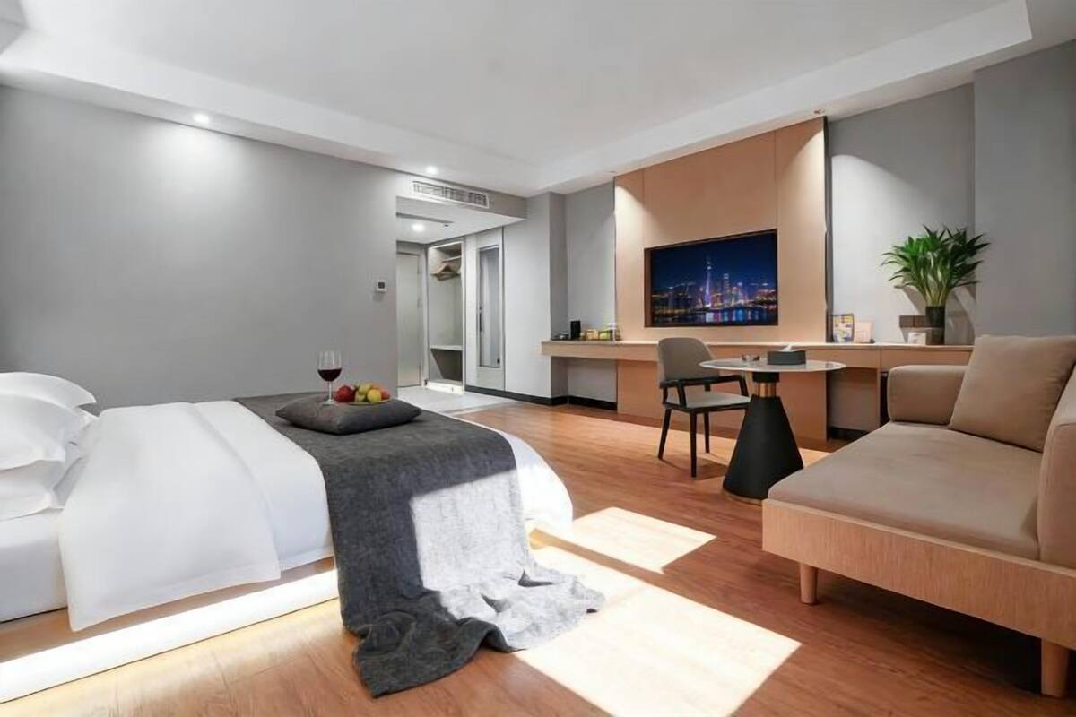 Una habitación de hotel moderna con cama, sofá, escritorio y televisor.