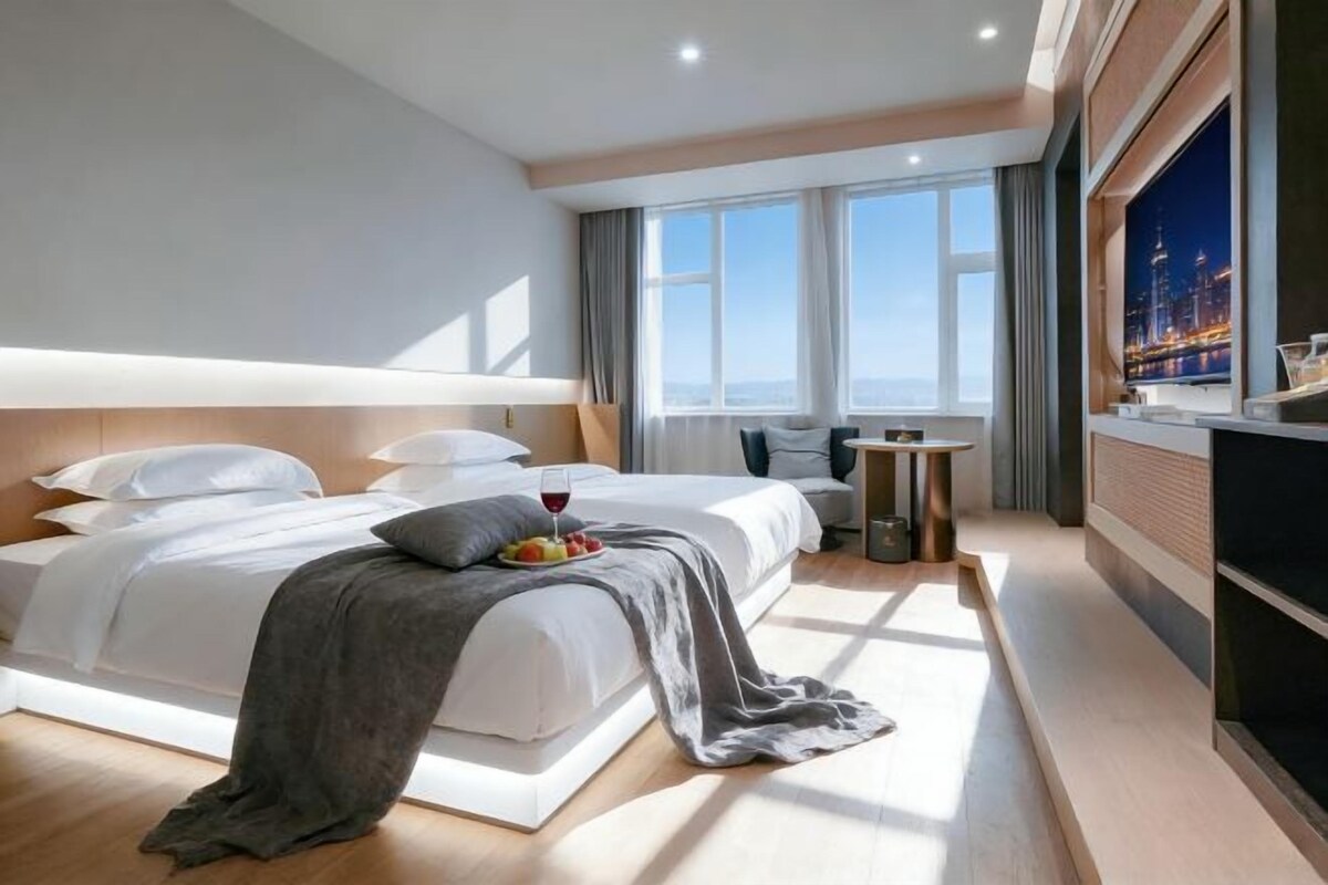 Une chambre d’hôtel moderne avec un grand lit, une petite table et un téléviseur.