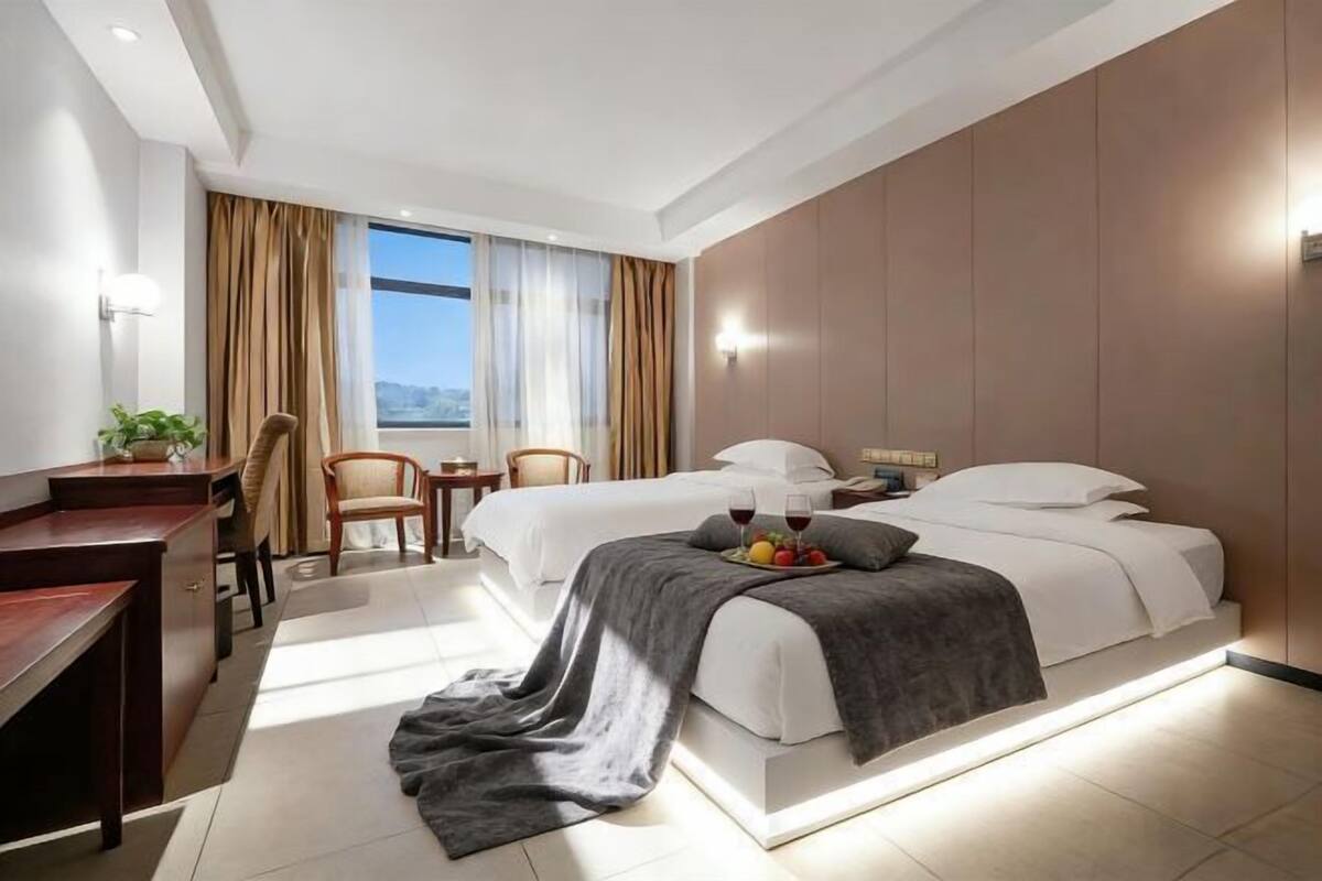 Habitación de hotel con cama, escritorio, sillas y vistas al exterior.