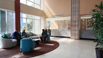 A spacious lobby with a reception desk, seating area, and large windows.