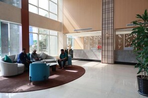 Un vestíbulo amplio con mostrador de recepción, zona de estar y grandes ventanales.