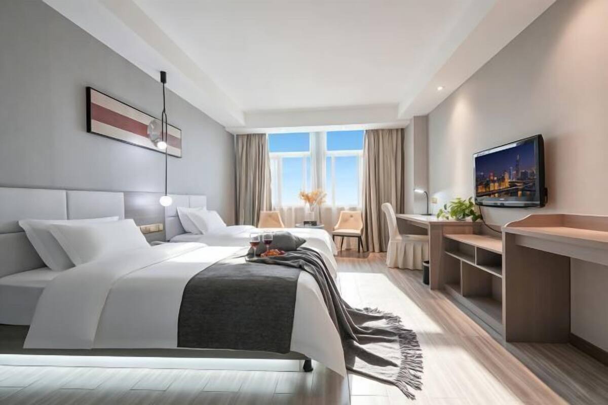 Un hotel moderno con una cama grande, un escritorio, un televisor y vistas a la ciudad desde la ventana.
