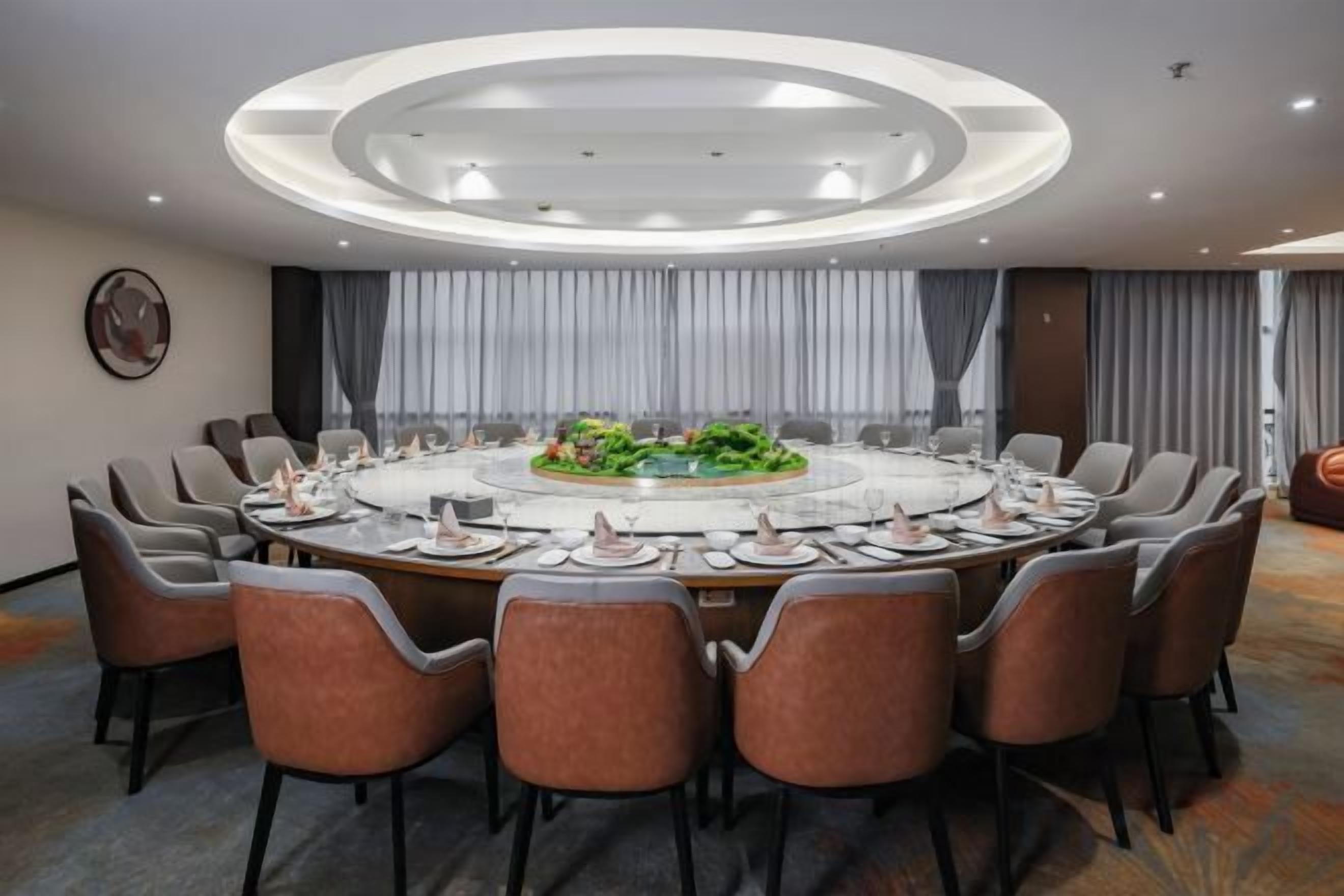 A conference room with a round table, chairs, and a central floral arrangement.