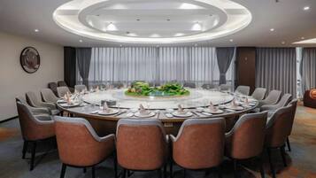 A conference room with a round table, chairs, and a central floral arrangement.