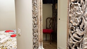 A room with a bed, a chair, and a mirror with ornate designs. - Cupido Suite by Ca-sa Check (Venice)