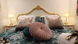 A bed with a decorative headboard, multiple pillows, and two bedside lamps.
