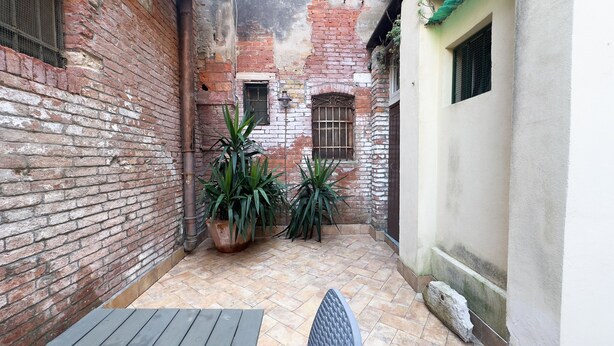 A narrow courtyard with brick walls, tiled flooring, and potted plants. - Cupido Suite by Ca-sa Check (Venice)