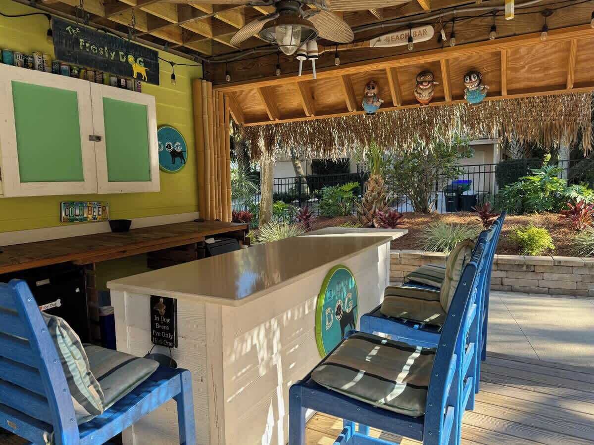 Una zona de bar con techo de madera, una barra y sillas azules.