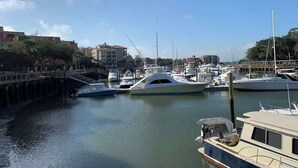 Un puerto deportivo con varios yates amarrados, un puente y edificios al fondo.
