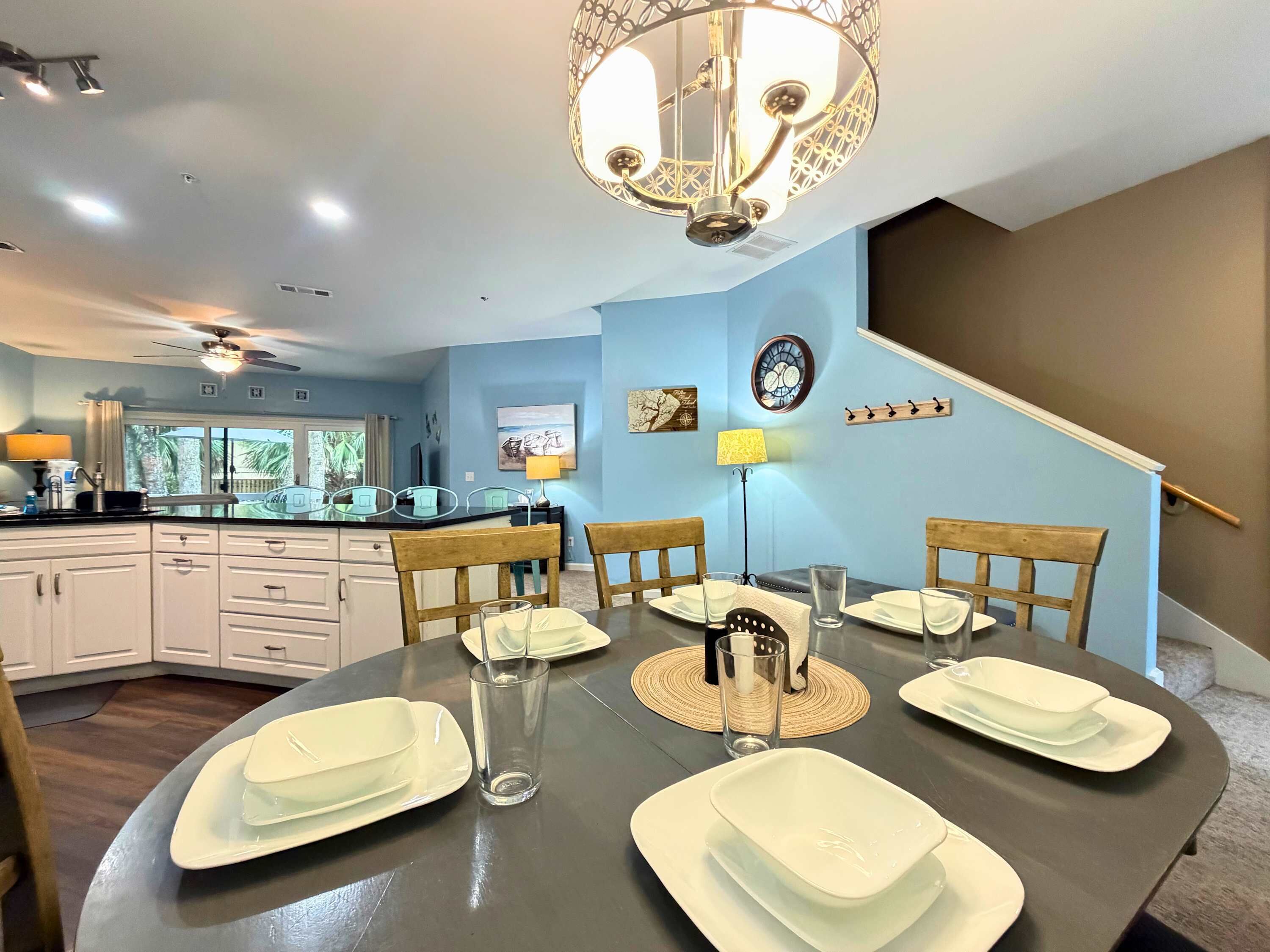 Uma cozinha moderna com armários brancos, uma mesa de jantar posta com pratos e copos brancos, e um candelabro.