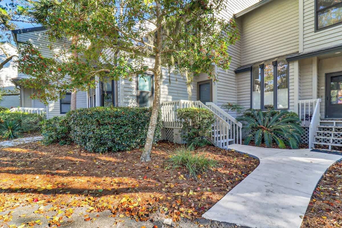 A residential building with a front yard, a concrete pathway, and a white picket fence.