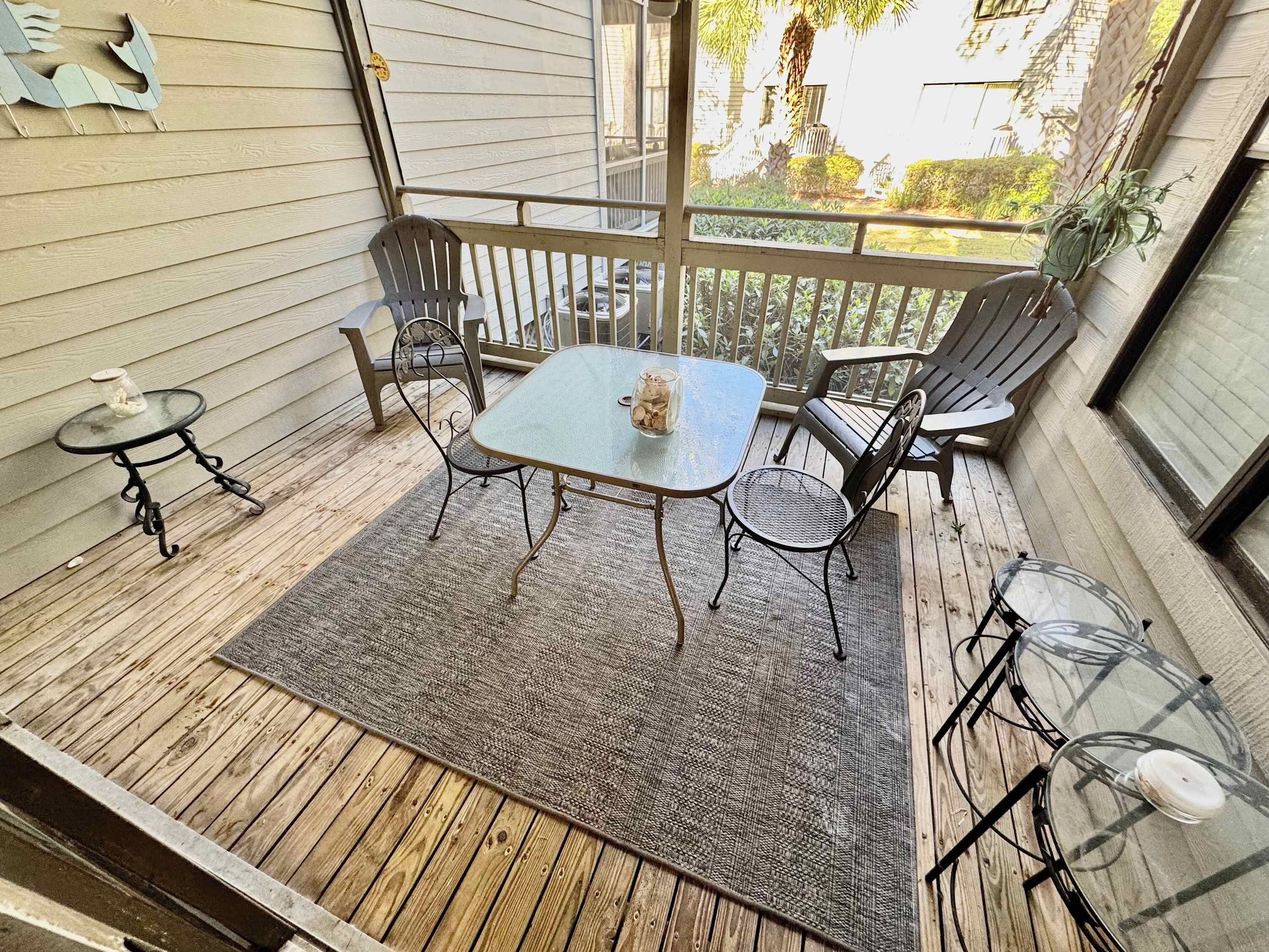 A covered patio with a glass-top table, four chairs, and a small side table.
