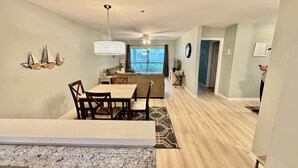 A spacious living area with a dining table, chairs, a patterned rug, and a ceiling fan. - Pet Friendly Beach Villa 2 Bed 2 Bath #7105 TreeTops (Hilton Head Island)