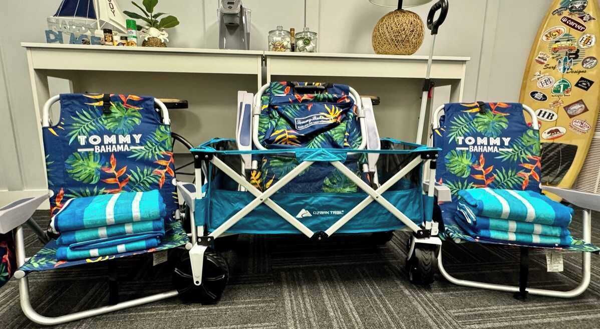 A room with two Tommy Bahama branded chairs, a small table, and a surfboard on the wall.