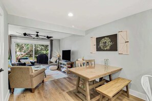 A spacious living area with a wooden dining table, a sofa, and a TV.